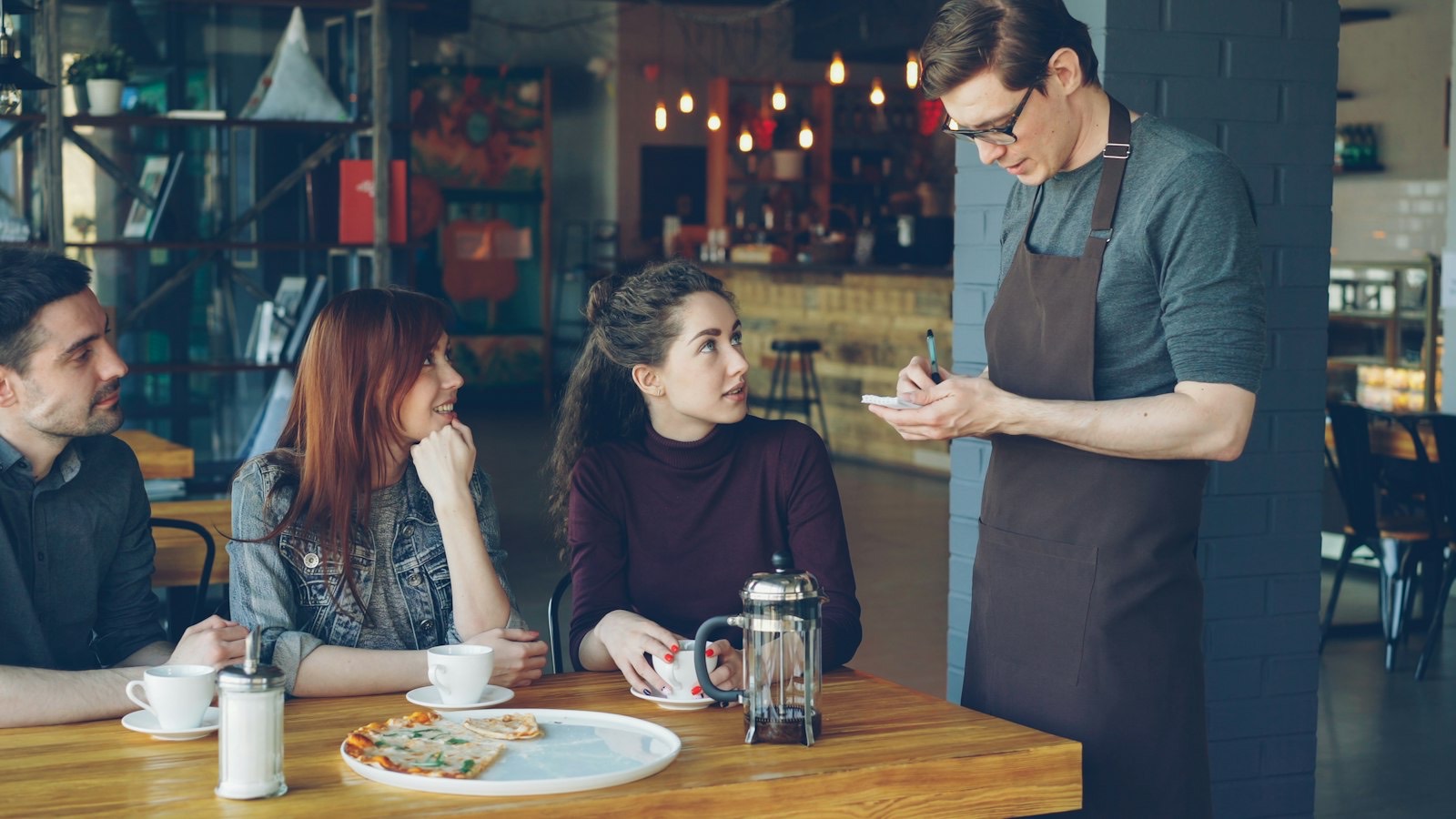 Ober neemt de bestelling op bij twee gasten in een café