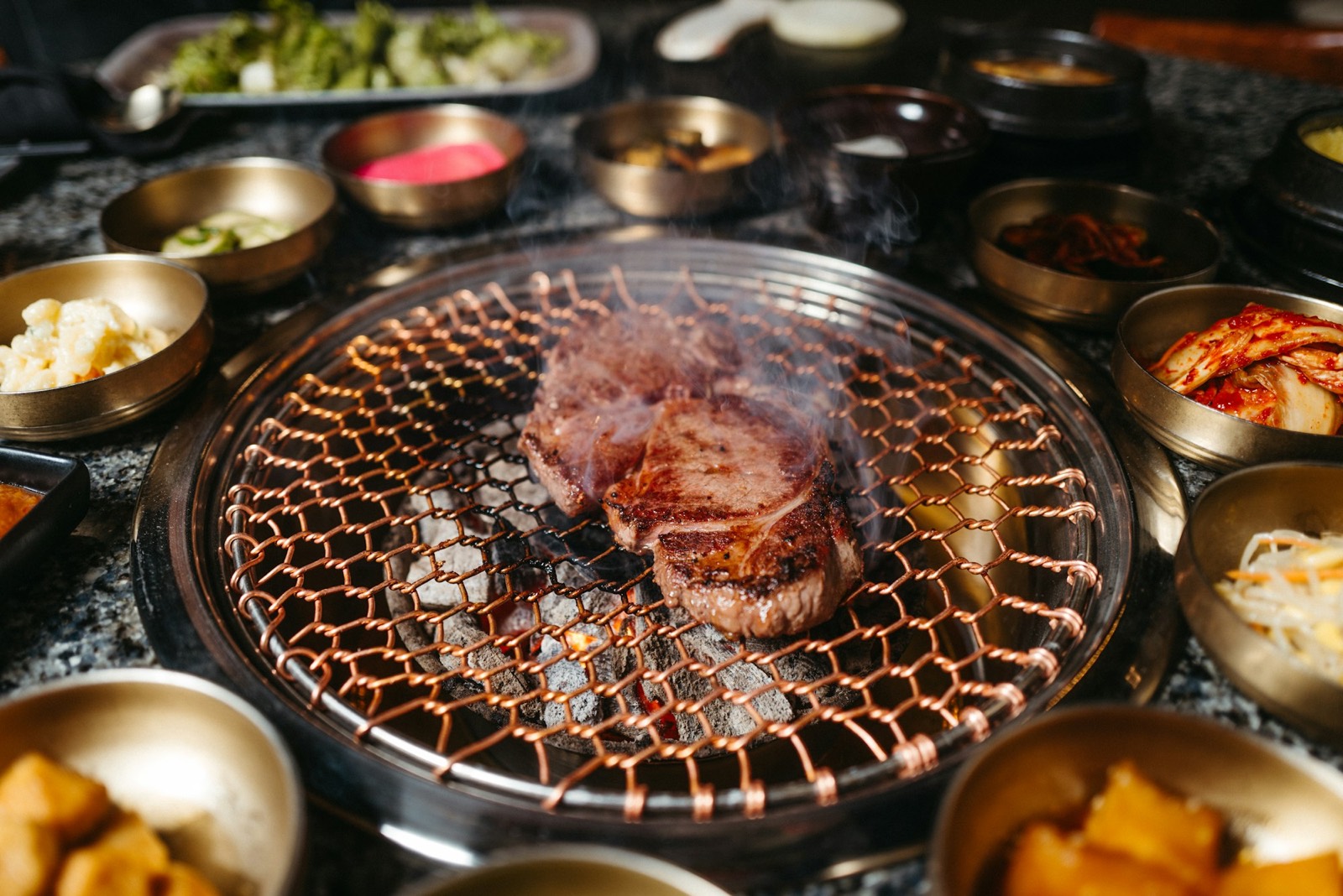 Vlees op een tafelgrill, met kleine bijgerechten eromheen