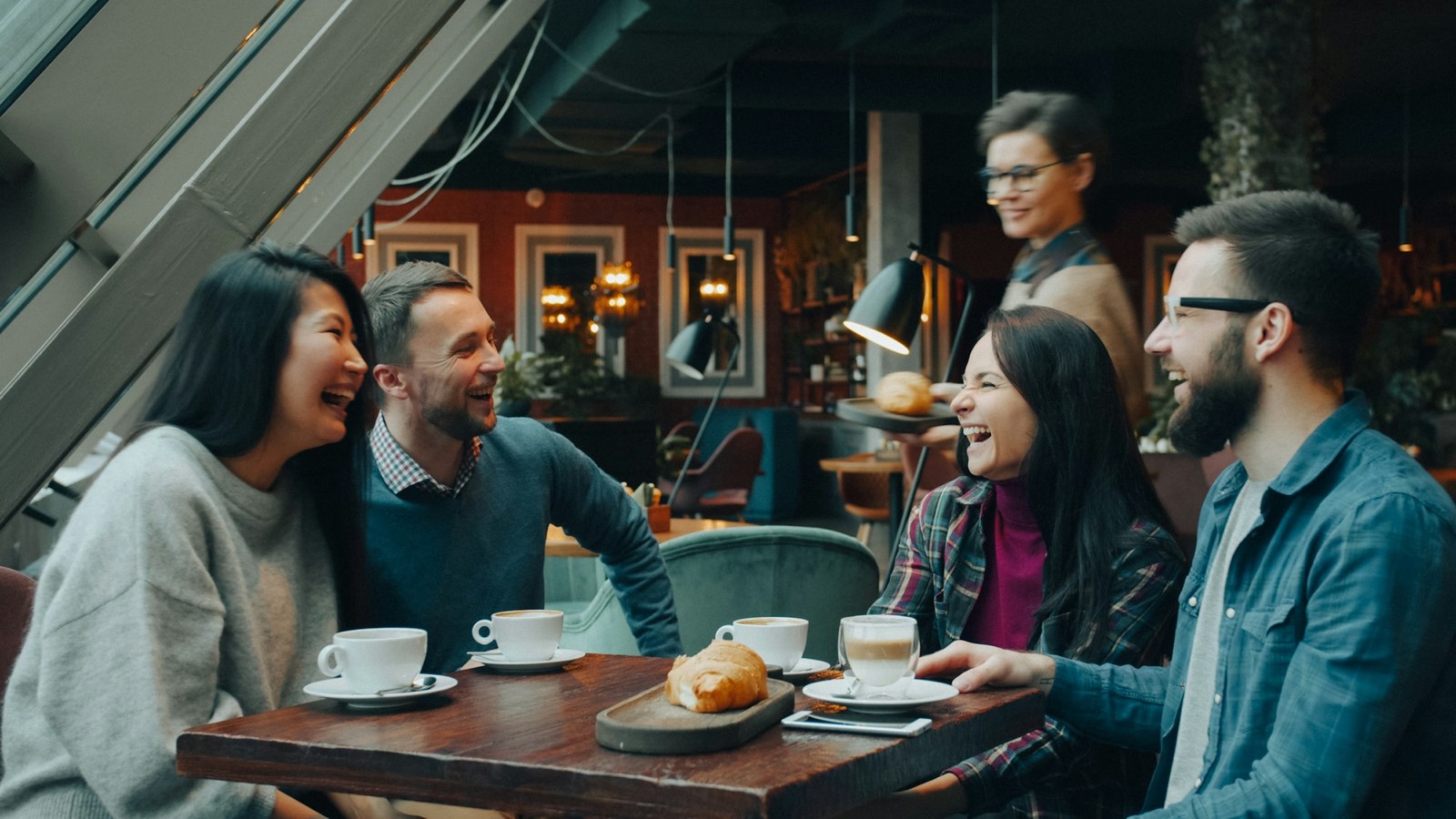 Staff member brings coffee and cake to a table of friends